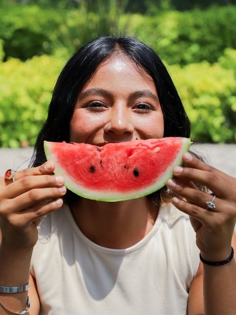 Estudante sorrindo com uma melancia para divulgar ebook de receitas